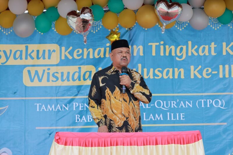 Kepala Dinas Syariat Islam Aceh Besar Rusdi S.Sos MSi menyampaikan sambutan pada Tasyakkur Kenaikan Tingkat IV dan Wisuda III TPQ Baburridha di halaman Mesjid Lam Ilie, Indrapuri, Minggu (22/06/2025). Foto: Dok. MC Aceh Besar