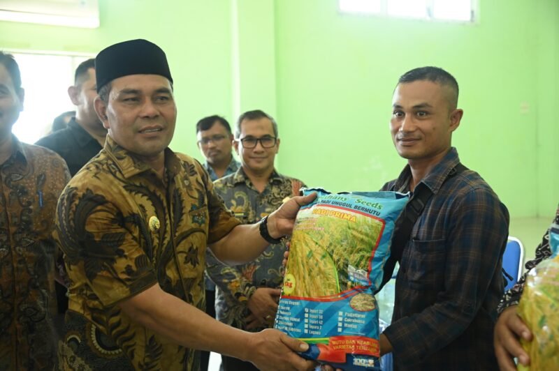 Bupati Aceh Besar H Muharram Idris didampingi Kepala Dinas Pertanian Aceh Besar Jakfar. SP, MSi menyerahkan bibit padi gogo jenis inpari 32 HDB kepada petani di 11 kecamatan di Aceh Besar, di Aula BPP Kuta Malaka, Kamis (26/6/2025). Foto: Dok. MC Aceh Besar