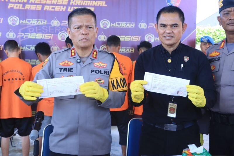 Kapolres & Kasat Reskrim menunjukkan barang bukti kwitansi tanda terima uang dari korban penipuan IKN. Dok. Polres Aceh Utara