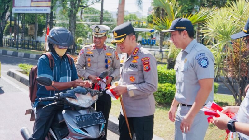Polresta Banda Aceh menggelar aksi simpatik dengan membagikan dan memasang bendera Merah Putih kepada pengguna jalan. (Foto: Dok. Misri/Acehnow).