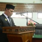 H Muharram Idris menyampaikan penjelasan Bupati Aceh Besar terhadap rancangan Qanun tentang pengelolaan keuangan daerah dan rancangan Qanun tentang penyelenggaran cadangan pangan, bertempat di Ruang Rapat Paripurna DPRK,Kamis (18/09/2025). dok. MC Aceh Besar