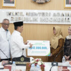 Wamenag Romo Syafi’i menyerahkan santunan kepada keluarga almarhum petugas haji Budi Iskandar Pulungan. dok. Kemenag RI