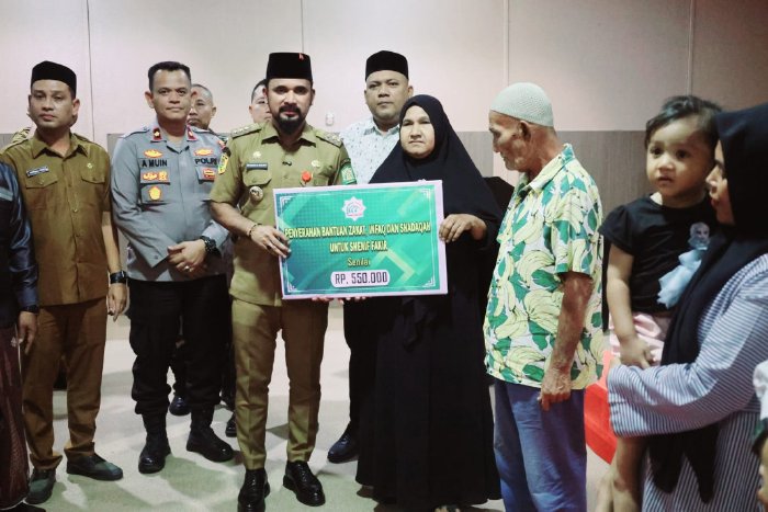 Bupati Aceh Timur, Iskandar Usman Al-Farlaky, S.H.I., M.Si., menyalurkan secara simbolis dana Zakat, Infak, dan Sedekah (ZIS) yang dikelola oleh Badan Baitul Mal Kabupaten Aceh Timur. Kegiatan berlangsung di Aula Graha Bunda, Idi, Senin (20/10/2025). dok. Pemkab Aceh Timur