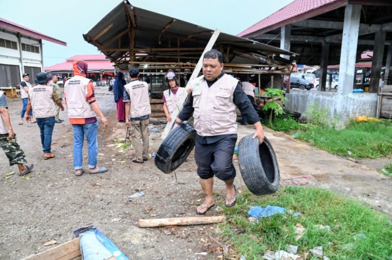 Plt Kadiskomugdag Aceh Besar, Drs Sulaimi MSi mengangkat sampah yang berserakan saat pembongkaran lapak pedagang yang berjualan di pinggir jalan untuk lahan parkir di Pasar Induk Lambaro, Kecamatan Ingin Jaya, Aceh Besar, Selasa (12/11/2025). FOTO: MC ACEH BESAR