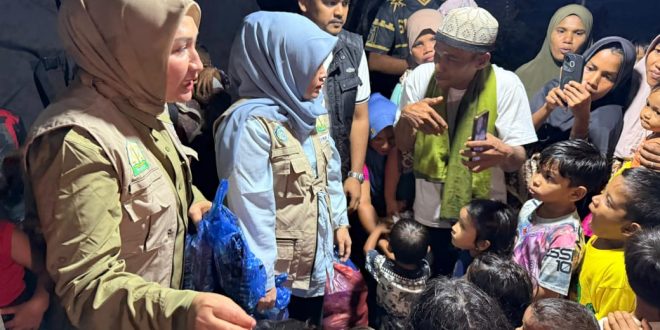 Ketua TP PKK Aceh Marlina Muzakir menyerahkan bantuan dan menyapa anak-anak pengungsi korban banjir bandang di Meunasah Gampong Paya Rubek, Kecamatan Sawang, Aceh Utara, Senin (22/12/2025) malam. Foto: Dok. Biro Adpim Setda Aceh 