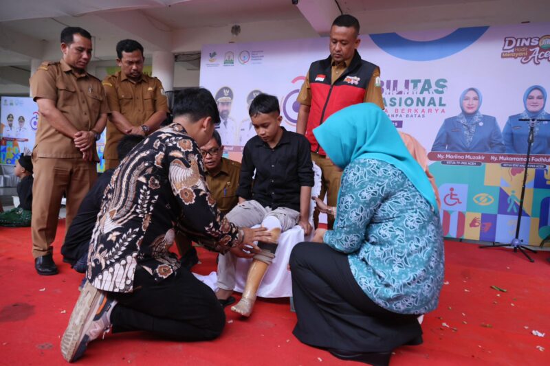 Plt. Kepala Dinas Sosial Aceh Chaidir bersama Ketua TP PKK Aceh Marlina Muzakir saat menyerahkan bantuan kaki palsu kepada penyandang disabilitas pada peringatan Hari Disabilitas Internasional 2025 di Banda Aceh, Selasa (30/12/2025). Foto: Dok. Istimewa
