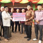 Kadis PMG Aceh Besar, Jakfar SP, M.Si, menyerahkan 100 sak semen secara simbolis kepada Imuem Meunasah Gampong Leu Ue di Pasar Mini BUMG Gampong Leu Ue, Kecamatan Darul Imarah, Aceh Besar, Kamis (19/2/2026). Foto: Dok. Mc Aceh Besar