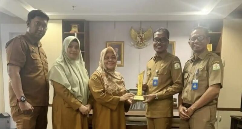 Kepala Dinas Perpustakaan dan Kearsipan Aceh (DPKA), Syaridin (kedua kanan), bersama jajaran staf menunjukkan piala penghargaan dari Arsip Nasional Republik Indonesia (ANRI) atas capaian digitalisasi arsip dengan predikat AA, di Banda Aceh, Selasa (24/2/2026). Foto: Dok. Istimewa 