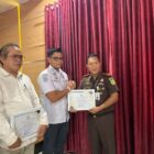 Kajari Aceh Besar Jemmy Novian Tirayudi, SH MH MSi menyerahkan piagam penghargaan kepada Kasatpol PP dan WH Aceh Besar Muhajir SSTP MAP, di Aula Baharuddin Lopa Kejari Aceh Besar, Kota Jantho, Rabu (25/2/2026). Foto: Dok. MC Aceh Besar