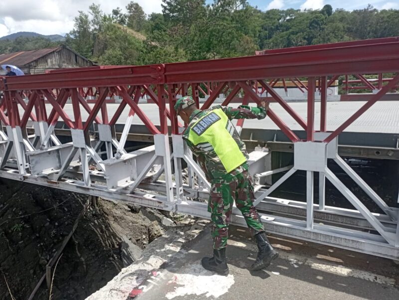 Ket foto : Babinsa Koramil 02/WPS melakukan pengecekan kondisi rangka dan baut pengunci Jembatan Bailey di Desa Jamur Ujung.(Dok/Ist)