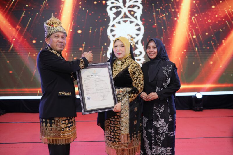 Bupati Pidie Jaya Tgk. H. Syibral Malasyi, S. Sos. Menyerahkan sertifikat HAKI atas tiga motif khas Pidie Jaya kepada Ketua Dekranas Kab. Pidie Jaya Hj. Asmawati yang turut di dampingi Sang pencipta Motif Wardatuttiflah. Meureudu, 14/6/2026. Foto:Dok/Muhammad Rissan 