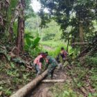 Keterangan Foto: Babinsa Koramil 09/Ketol Sertu Sopian bersama warga Desa Bah melaksanakan gotong royong menarik kayu.(Dok/Ist)