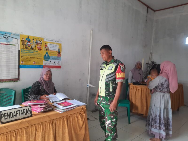 Keterangan Foto: Babinsa Koramil 09/Ketol membantu tenaga kesehatan saat pelaksanaan kegiatan Posyandu.(Dok/Ist)