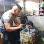 Aipda Candra Sugara, SH saat memangkas rambut pasien penderita gangguan saraf, Minggu (26/7/2026), di wilayah Kecamatan Bandar, Kabupaten Bener Meriah, sebagai bentuk kepedulian dan pelayanan humanis Polsek Bandar kepada masyarakat.(Dok: Rahmat Ramadhan/Acehnow.com)