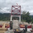 Personel TNI bersama masyarakat memasang papan lantai dan mengecat tiang penyangga dalam tahap akhir pembangunan Jembatan Gantung Perintis di Desa Kumbang Jaya, Kecamatan Badar, Aceh Tenggara, Kamis (6/8/2026). Foto: Dok. Istimewa