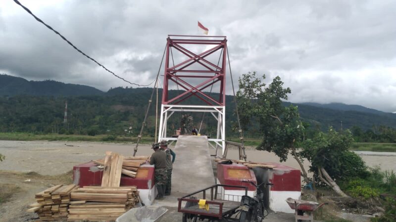 Personel TNI bersama masyarakat memasang papan lantai dan mengecat tiang penyangga dalam tahap akhir pembangunan Jembatan Gantung Perintis di Desa Kumbang Jaya, Kecamatan Badar, Aceh Tenggara, Kamis (6/8/2026). Foto: Dok. Istimewa 