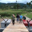 Babinsa Kodim 0108/Aceh Tenggara bersama masyarakat, teknisi, dan personel terkait bergotong royong memasang papan lantai Jembatan Gantung Perintis di Desa Kuta Ujung, Kecamatan Darul Hasanah, Kabupaten Aceh Tenggara, Selasa (4/8/2026). Foto: Dok. Istimewa
