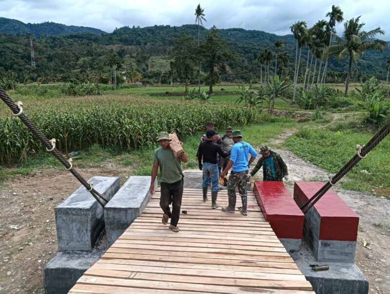 Babinsa Kodim 0108/Aceh Tenggara bersama masyarakat, teknisi, dan personel terkait bergotong royong memasang papan lantai Jembatan Gantung Perintis di Desa Kuta Ujung, Kecamatan Darul Hasanah, Kabupaten Aceh Tenggara, Selasa (4/8/2026). Foto: Dok. Istimewa 
