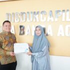 Kepala Disdukcapil Kota Banda Aceh, Heru Triwijanarko menyerahkan KK dan KTP kepada Mardalena dengan status pekerjaan sebagai pensiunan di Kantor Disdukcapil Kota Banda Aceh, Kamis (29/10/2026). Foto: Dok. Diskominfo Kota Banda Aceh